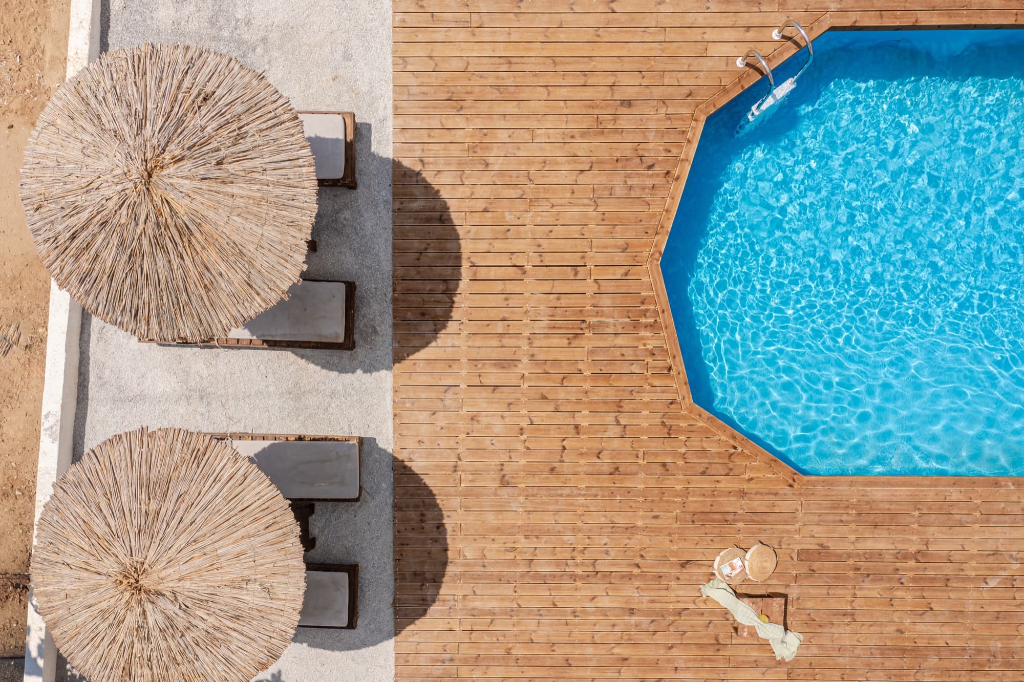Close-up aerial view of pool with straw umbrellas and sun loungers