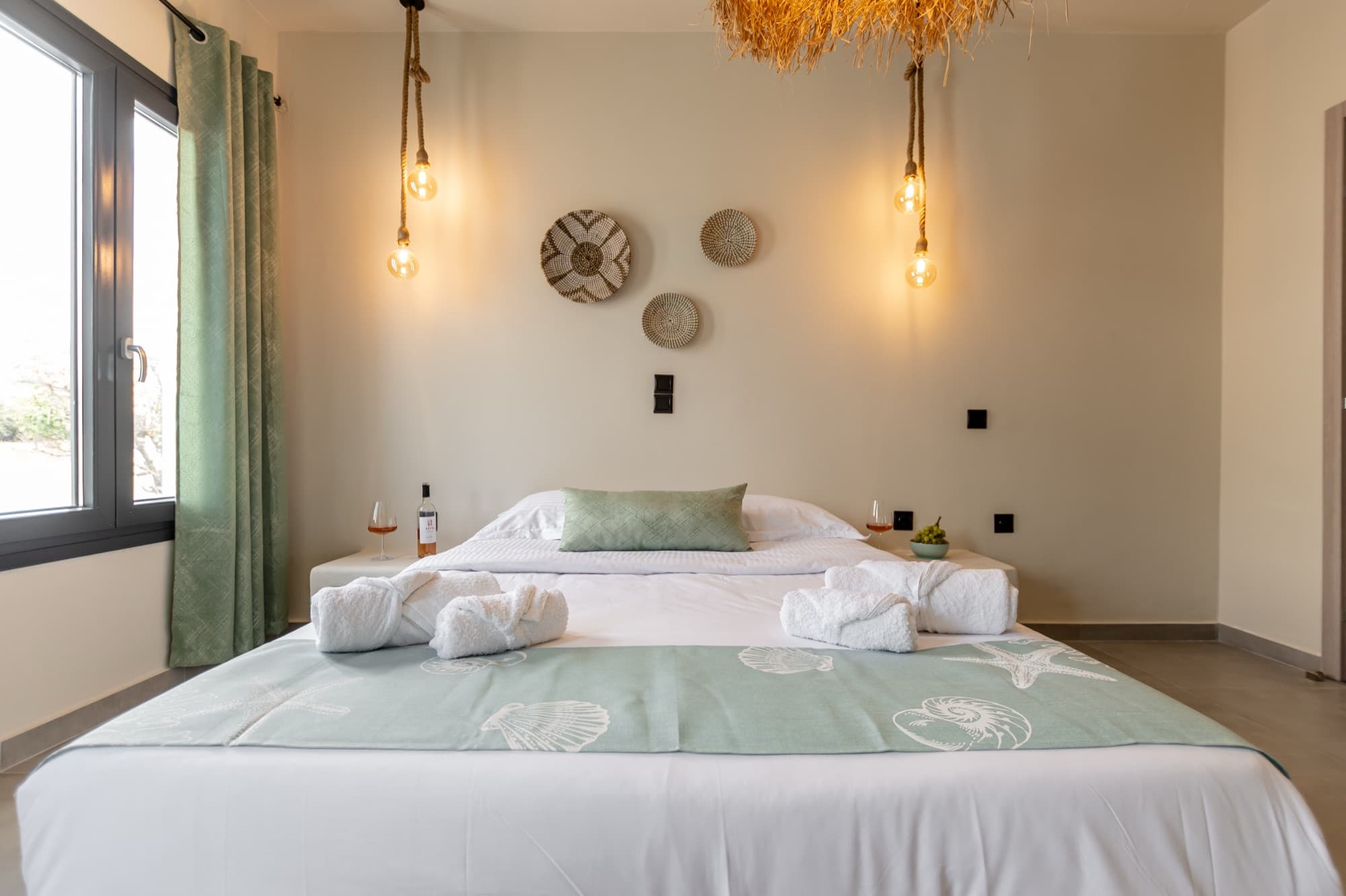 Master bedroom with sage green accents, rope pendant lights and woven wall decor